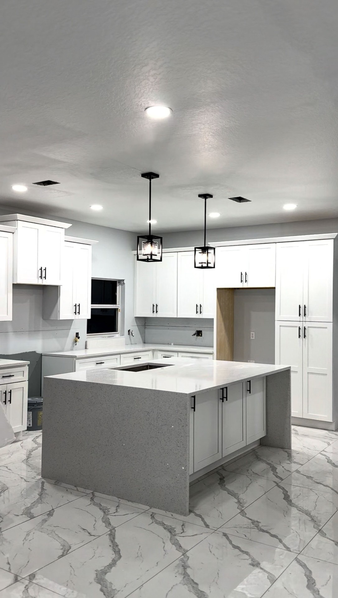 Modern white kitchen with quartz waterfall island and pendant lighting